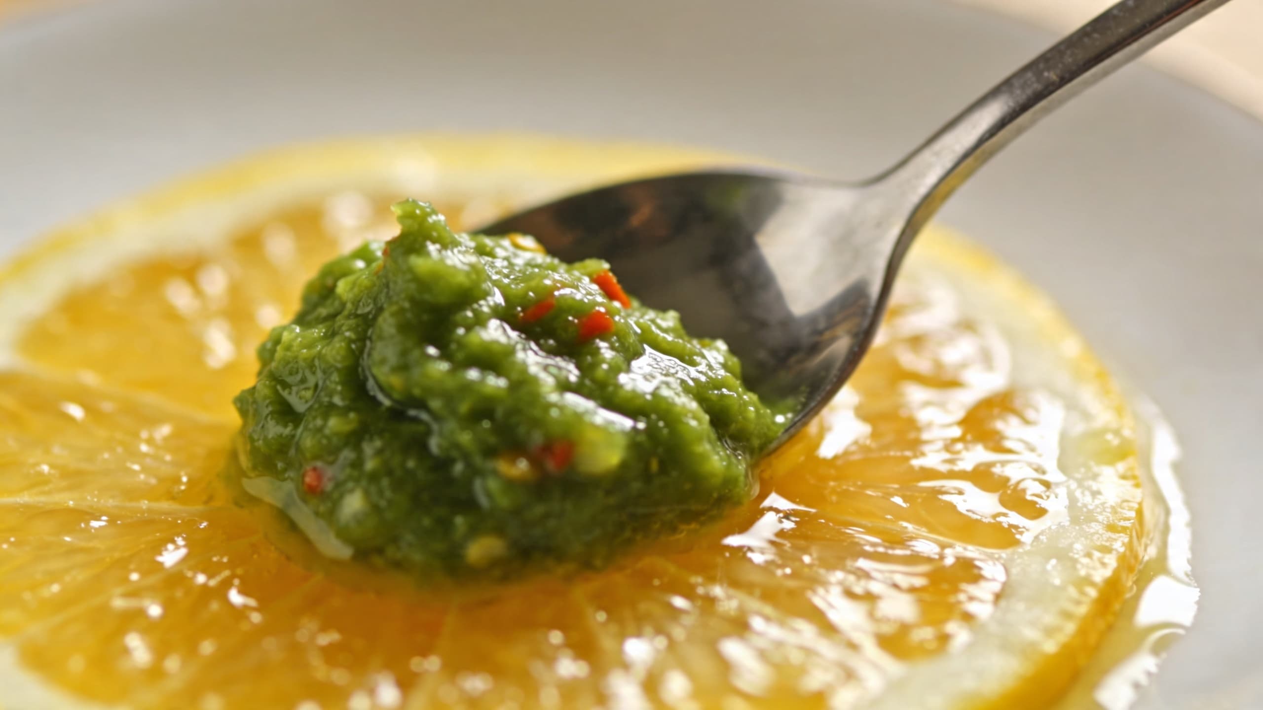 A close-up of vibrant green Yuzu Kosho being folded into a shimmering citrus glaze