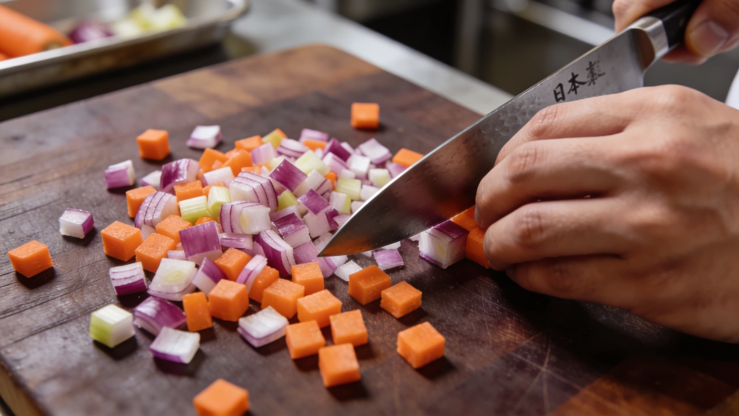 A precision brunoise of aromatics being prepared to build the flavor base for a smoky ragu.